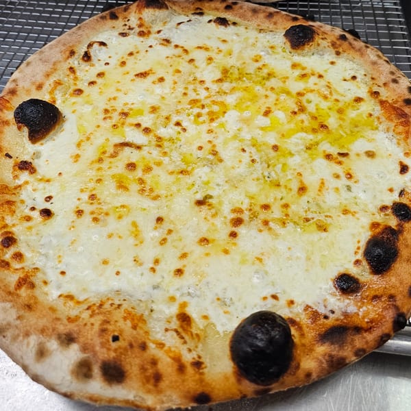 A freshly baked Pizzaluté white pizza with melted cheese and golden crust on a metal rack.